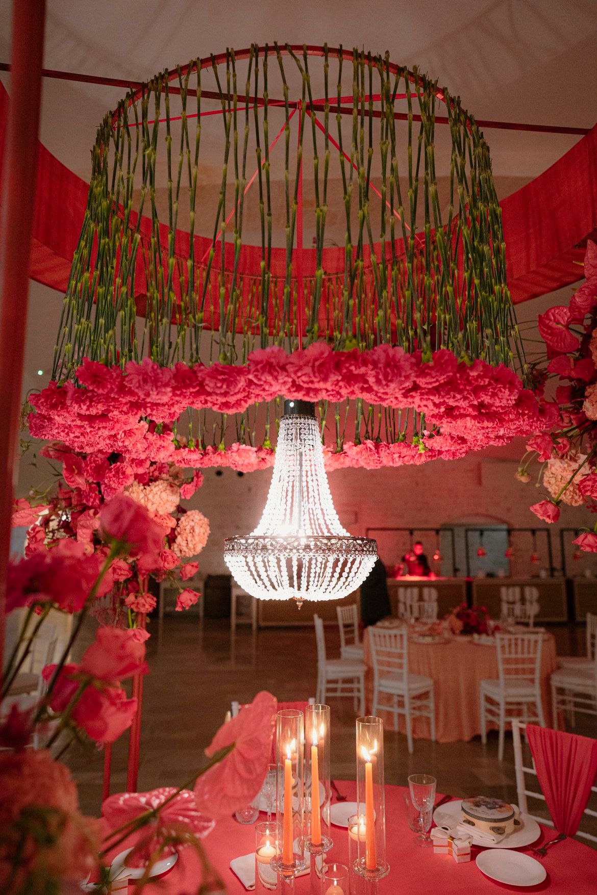 Chandelier floreale LIPPOLIS: installazione circolare con steli verdi, garofani fuchsia e lampadario di cristallo